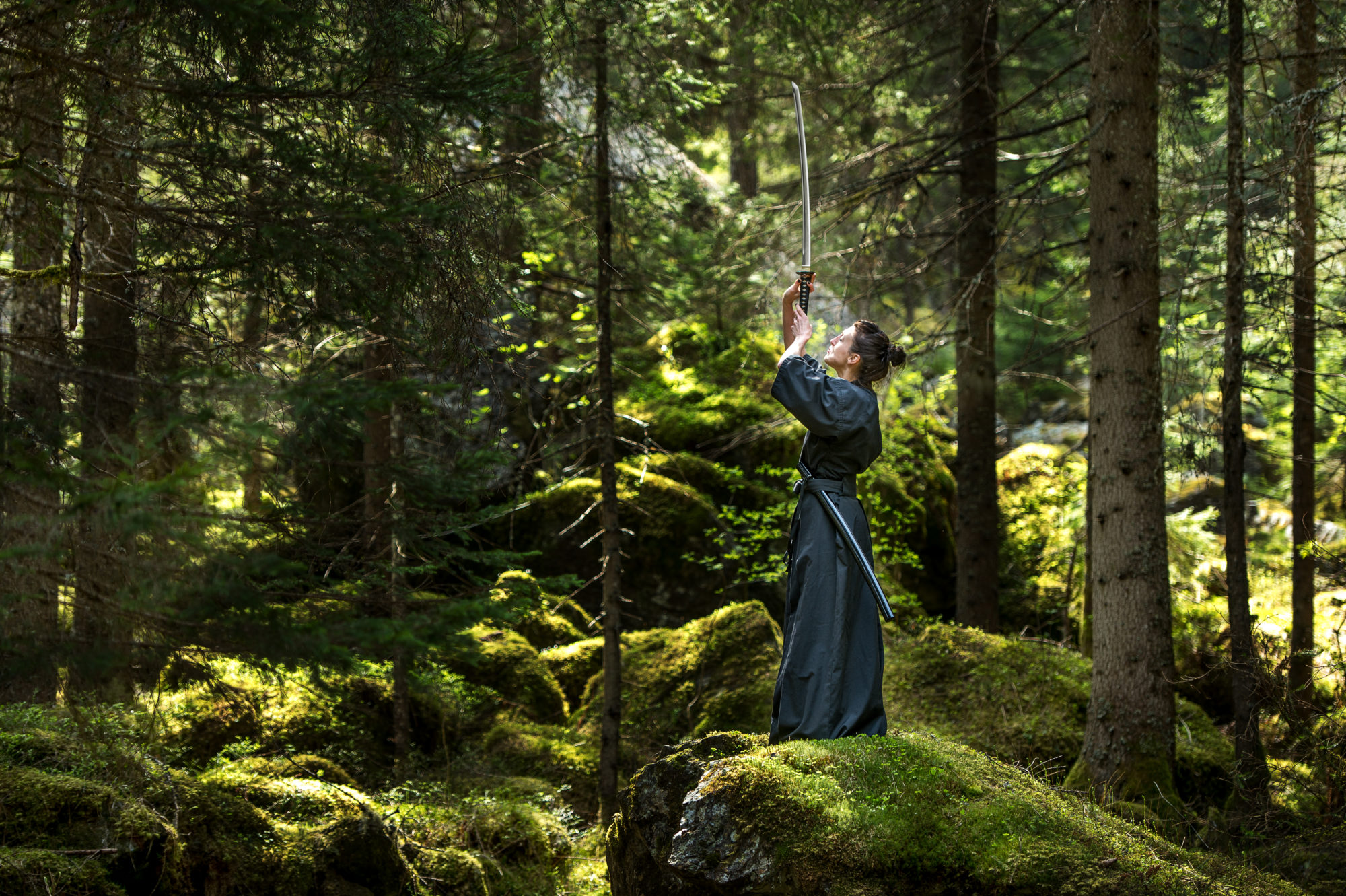 Foto di un atleta si esercita con la katana in ambiente naturale