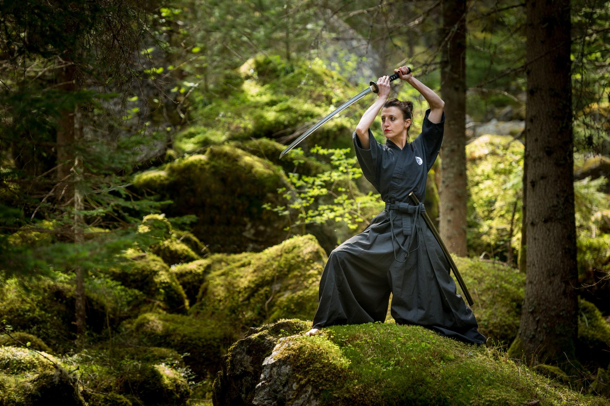 Foto di un atleta si esercita con la katana in ambiente naturale