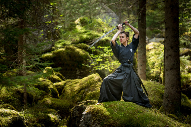 un atleta si esercita con la katana in ambiente naturale