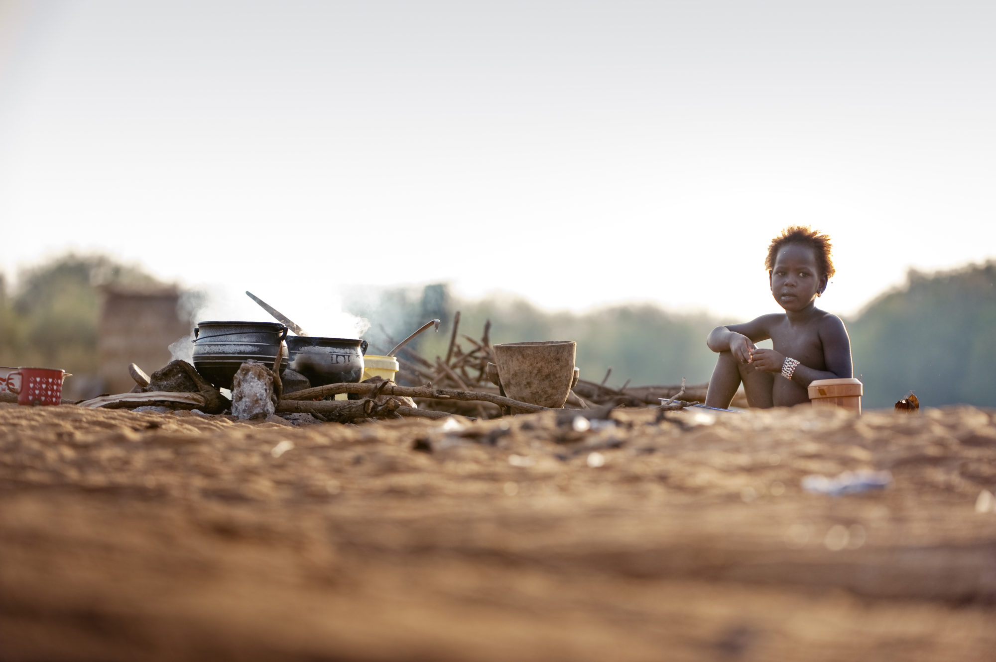 Foto di Bambina nomade che mangia su una spiaggia sul fiume Niger