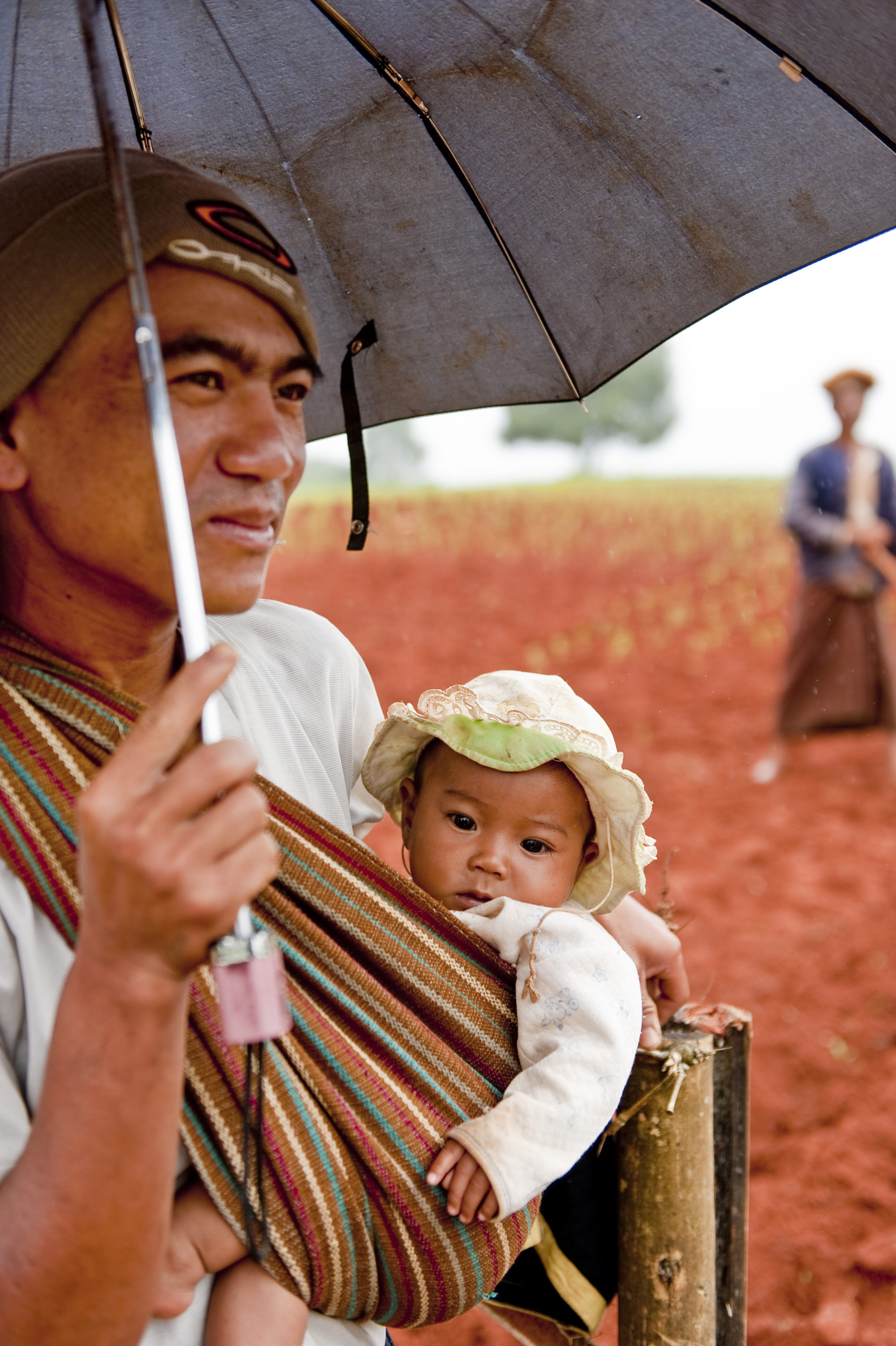 Foto di Padre e figlia sotto la pioggia in campagna in Myanmar