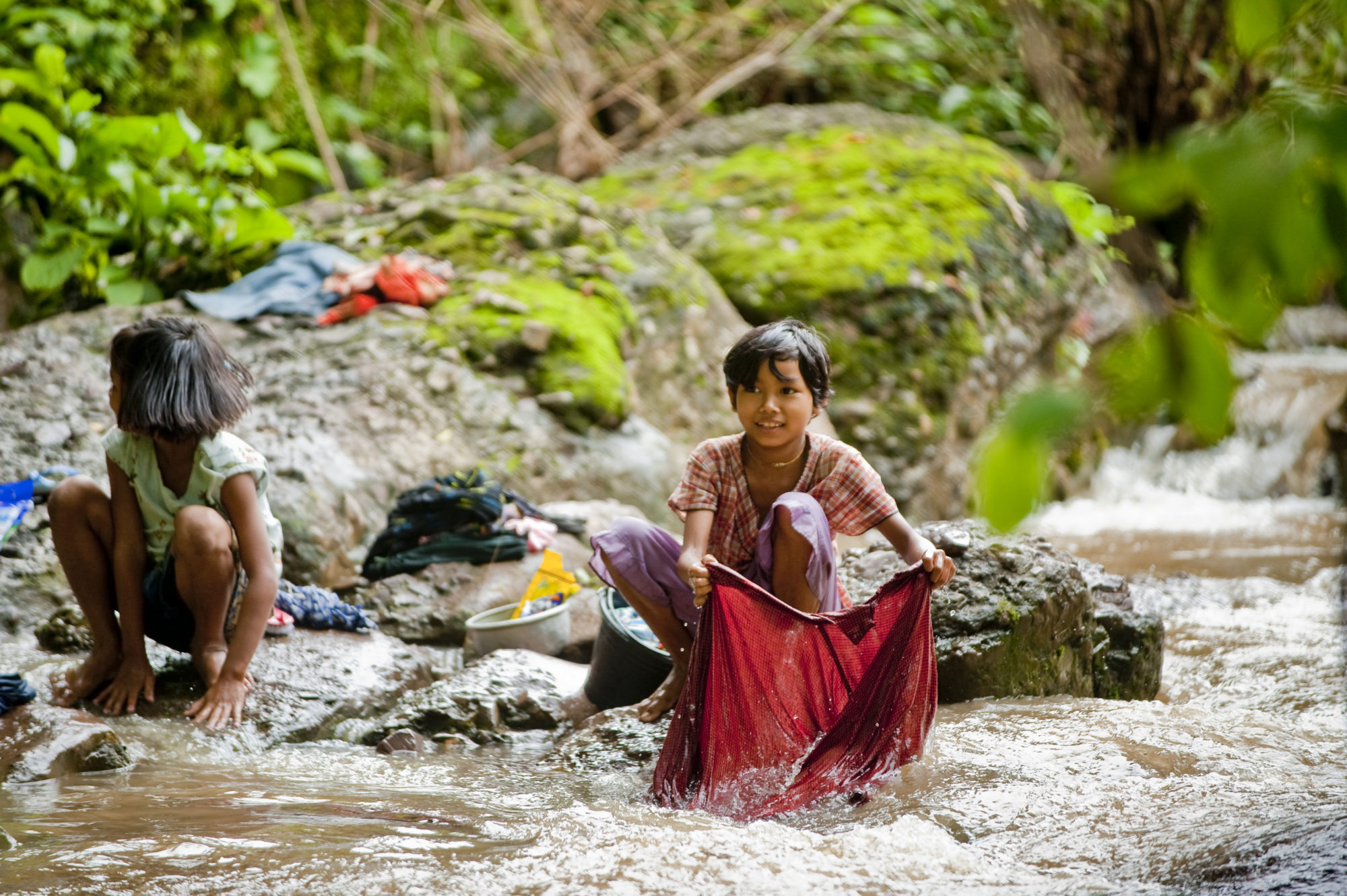 Foto di Bambine che lavano i panni in un fiume in Myanmar