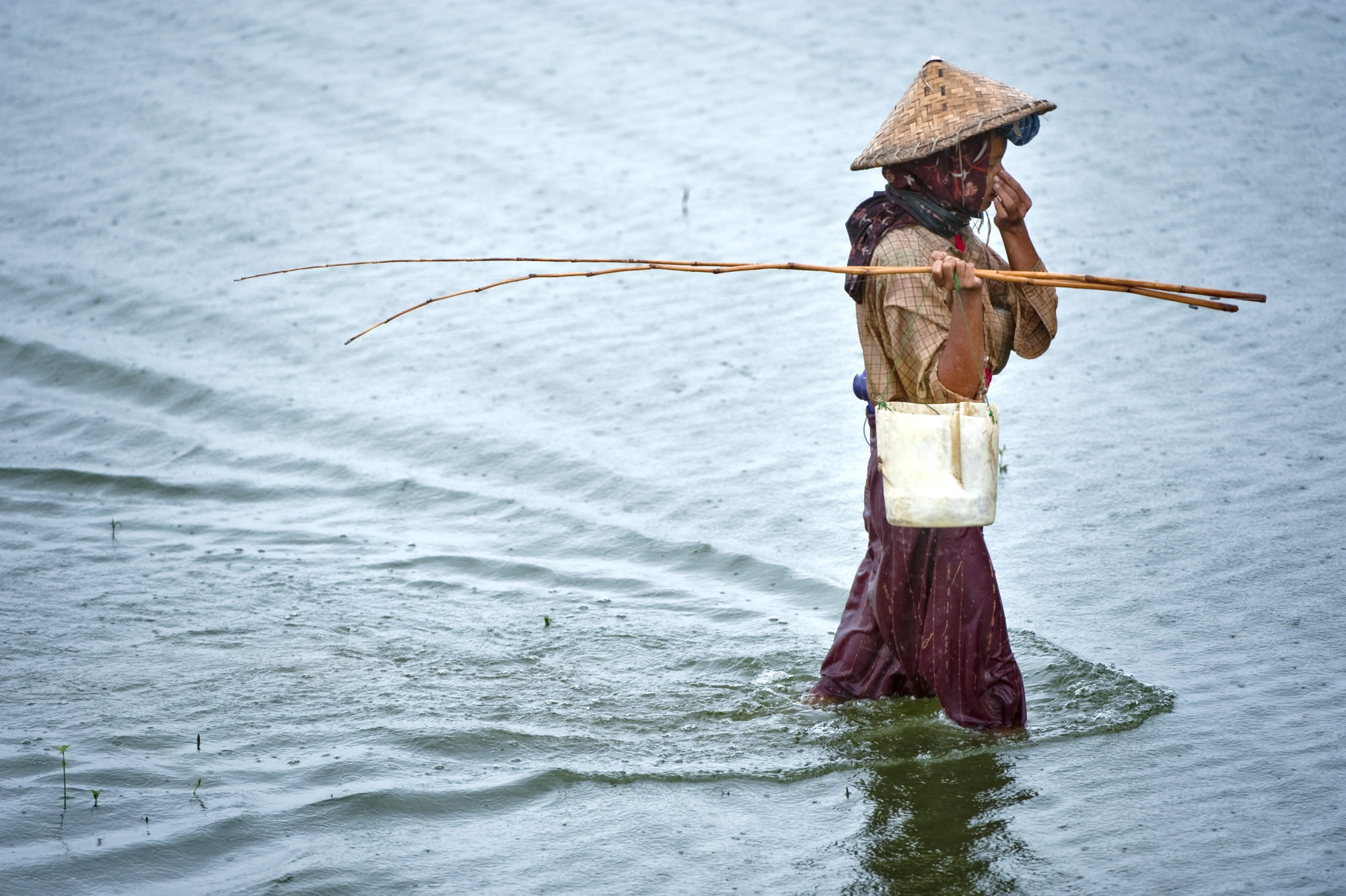 Foto di Pescatore al lavoro sul lago Inle in Myanmar sotto la pioggia