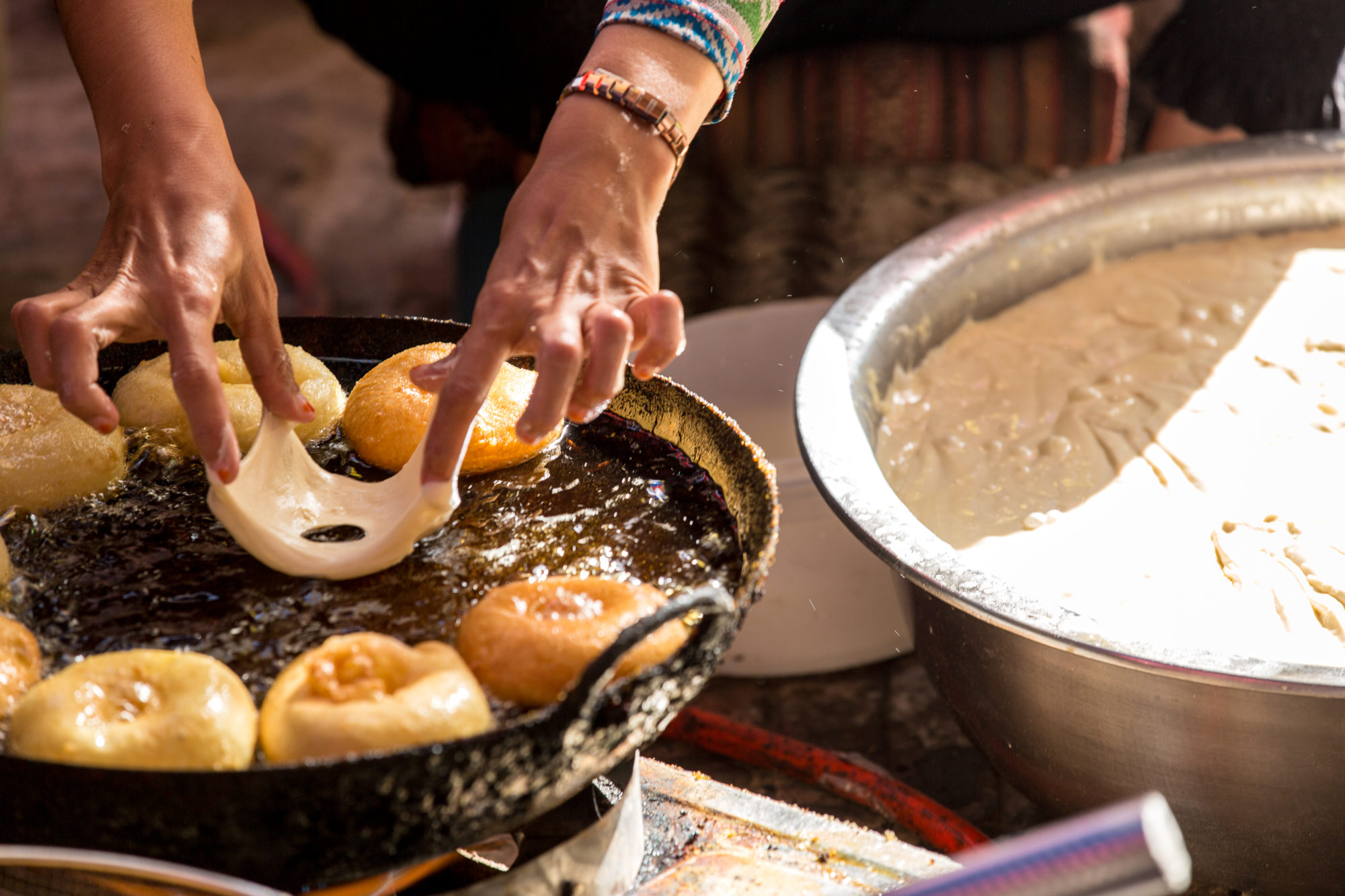 Foto di Una donna cucina frittelle al mercato di Kashgar