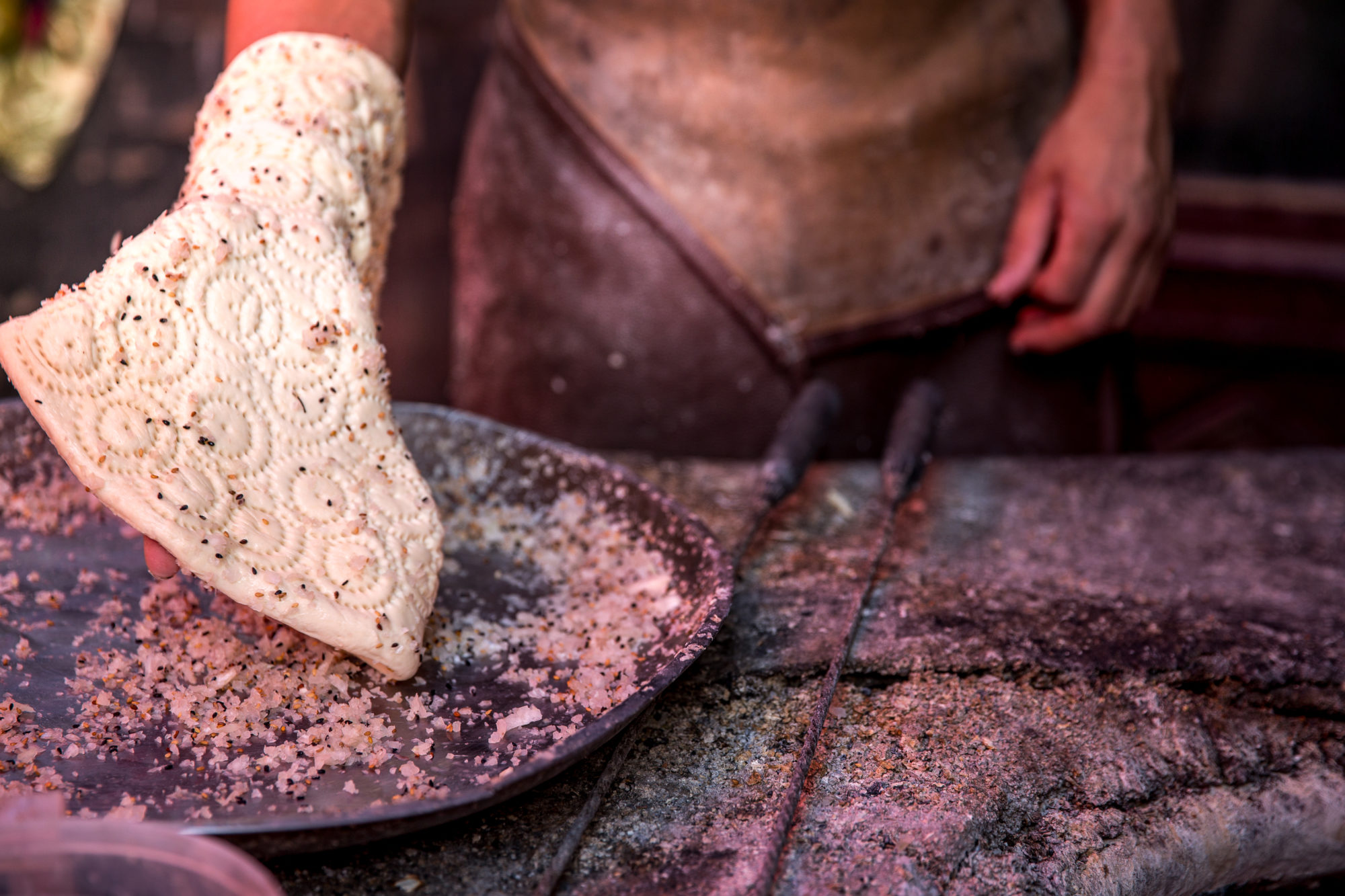 Foto di Kashgar. Un uomo prepara un particolare pane chiamato Nang