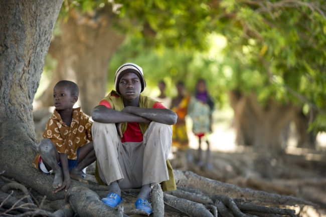 Due bambini seduti sotto ad un albero di mango