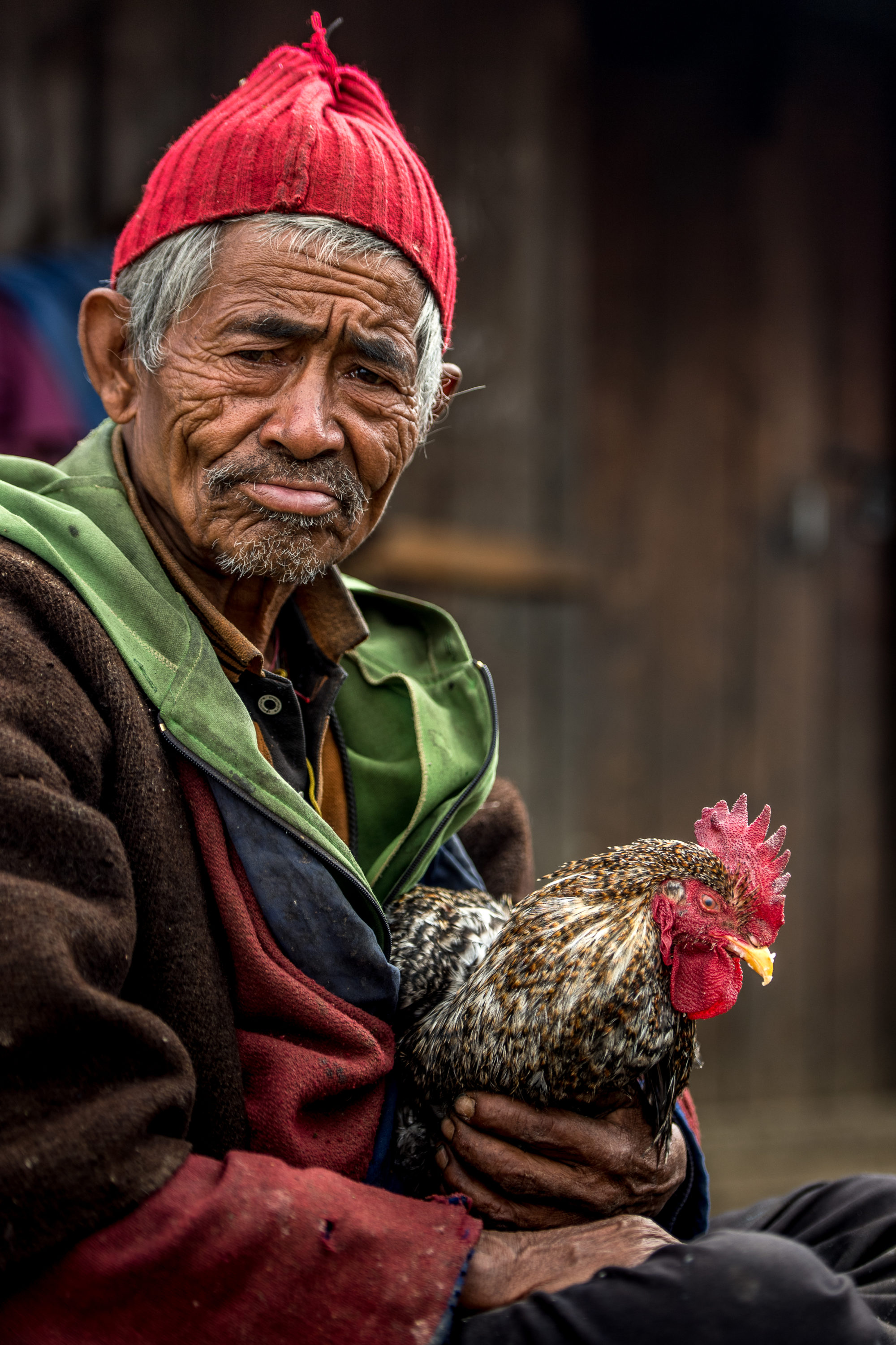 Foto di un uomo col suo gallo davanti alla sua casa nel tamang heritage